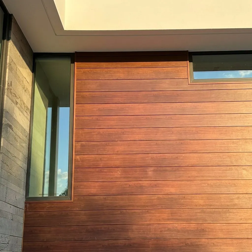 Mahogany-toned plank siding wrapping a wall between a vertical glass slot and a high window